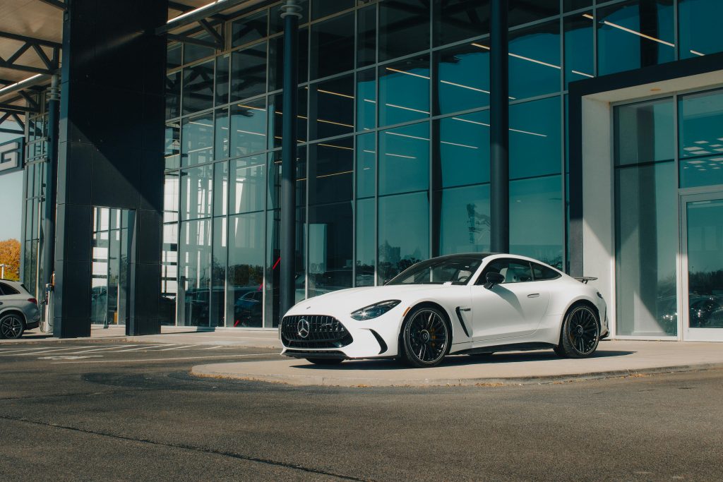Λευκή Mercedes-AMG GT μπροστά από γερμανική αντιπροσωπεία αυτοκινήτων – παράδειγμα ποιοτικού μεταχειρισμένου από τη Γερμανία.