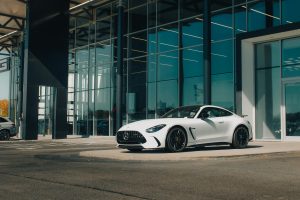 Λευκή Mercedes-AMG GT μπροστά από γερμανική αντιπροσωπεία αυτοκινήτων – παράδειγμα ποιοτικού μεταχειρισμένου από τη Γερμανία.